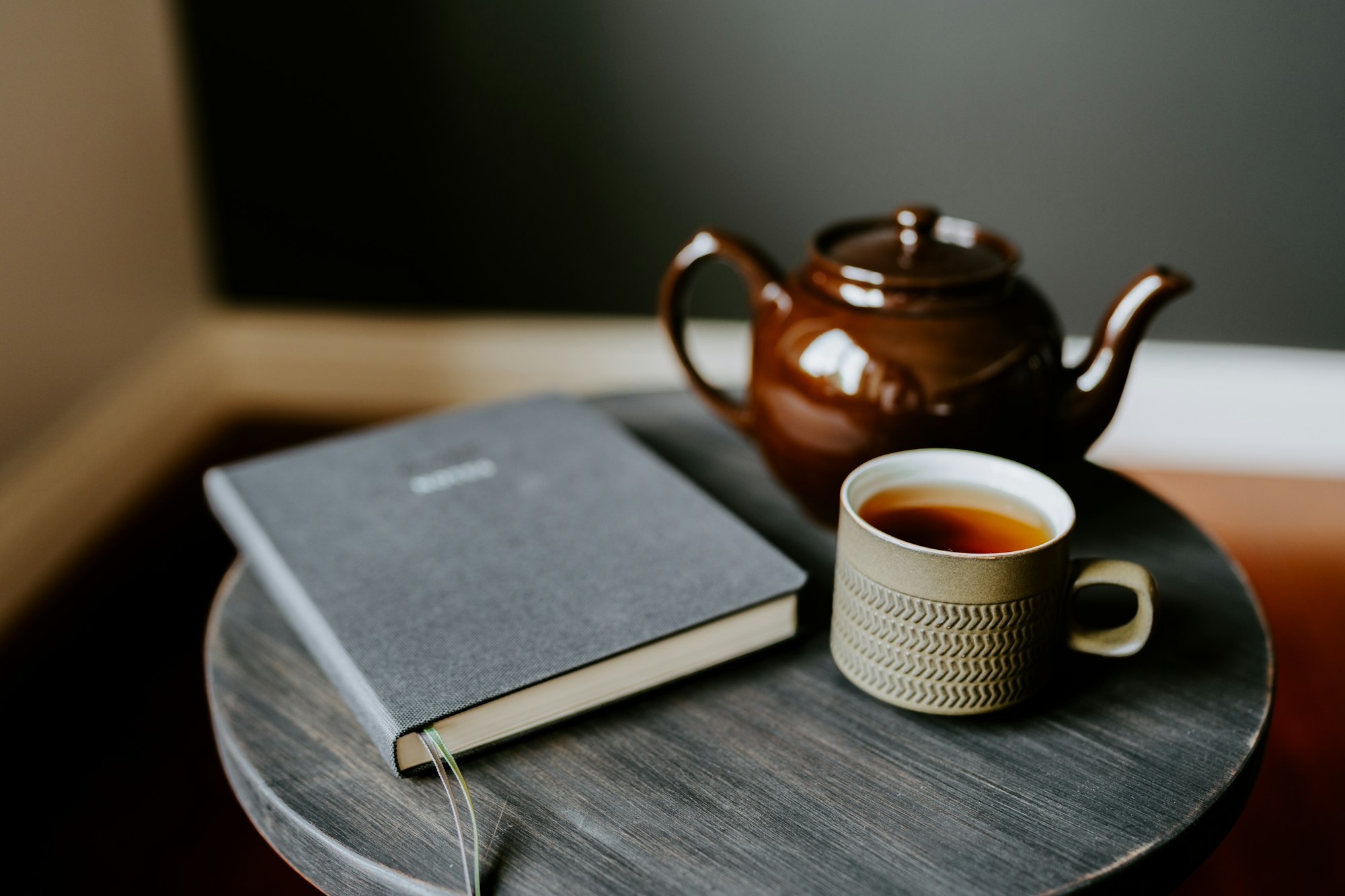 Eine Teekanne, eine Tasse Tee und ein Notizbuch auf einem runden Tisch